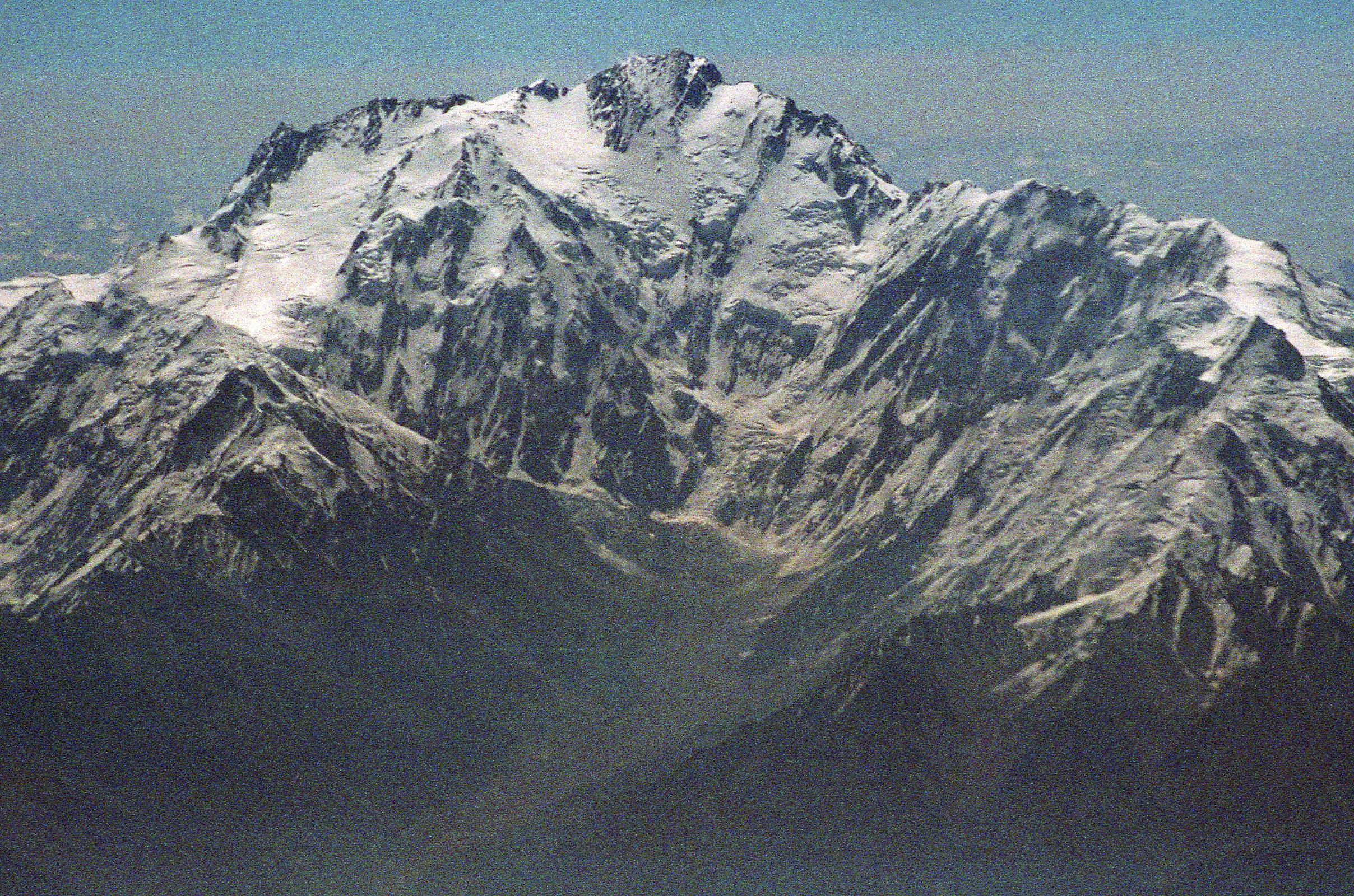 06 Nanga Parbat Diamir Face And Mazeno Ridge On Flight From Islamabad To Skardu On the 40-minute flight from Islamabad to Skardu, the captain announces, �We'll be flying at a planned altitude of 8,000 metres.� Perfect I thought, we'll be exactly at the height of Nanga Parbat. The flight starts low key with the stewardesses serving drinks while we bide our time. When the pilot announces �Nanga Parbat is immediately ahead on the right�, all hell breaks loose. As one, all the tourists, including me, are up in the aisles, craning their necks, running for the cockpit. The sounds of cameras are everywhere. There it is, within arms reach. Nanga Parbat in perfect early morning splendor! We are passing by the Diamir Face, as I click photo after photo. The massive Mazeno Ridge runs down to the right of Nanga Parbat. The Mazeno ridge is the longest ridge on any 8000m mountain and includes eight 7000m peaks. Nobody has managed to traverse the ridge and continue to the summit of Nanga Parbat.